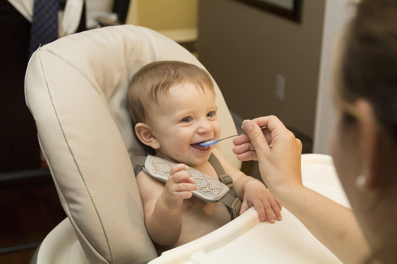 Child being fed while sitting in a high chair 