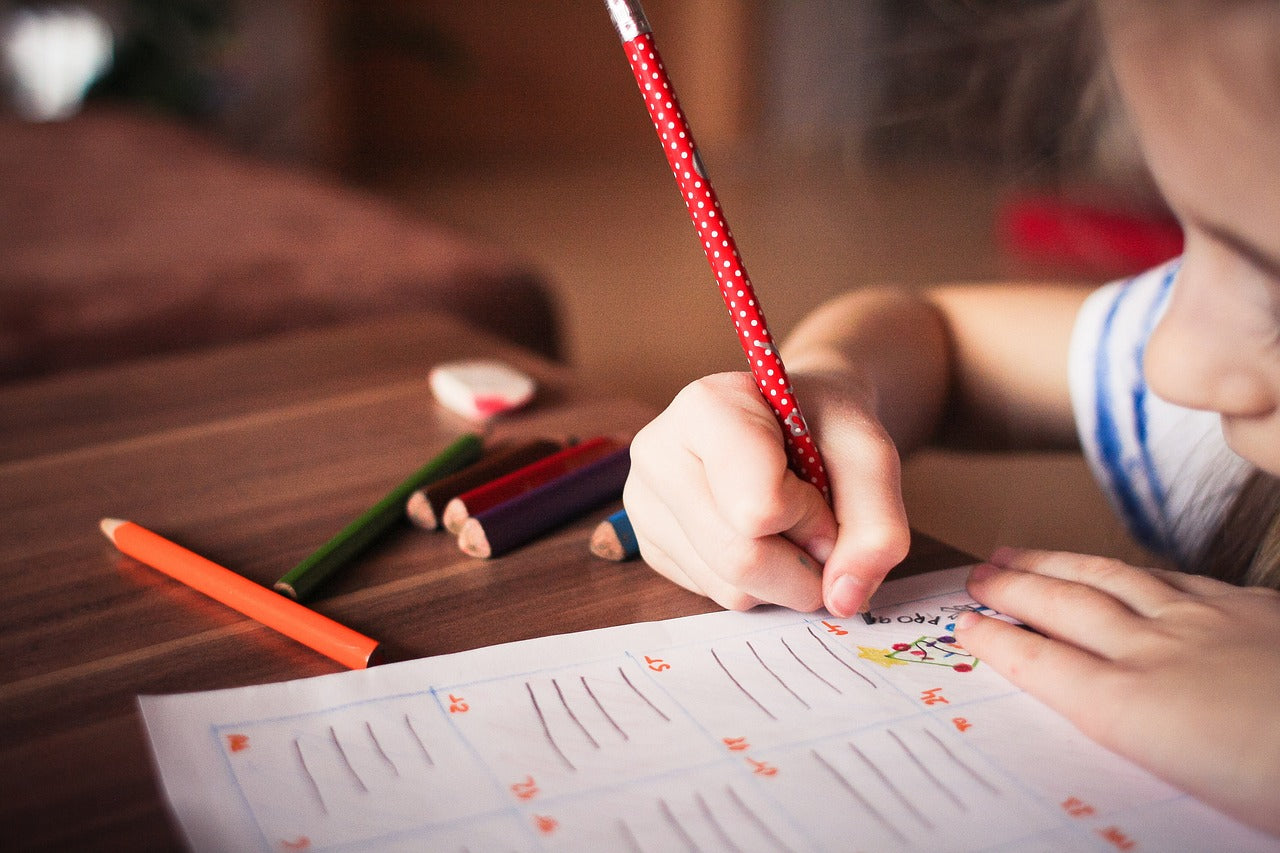 Child writing on paper sitting at a table 