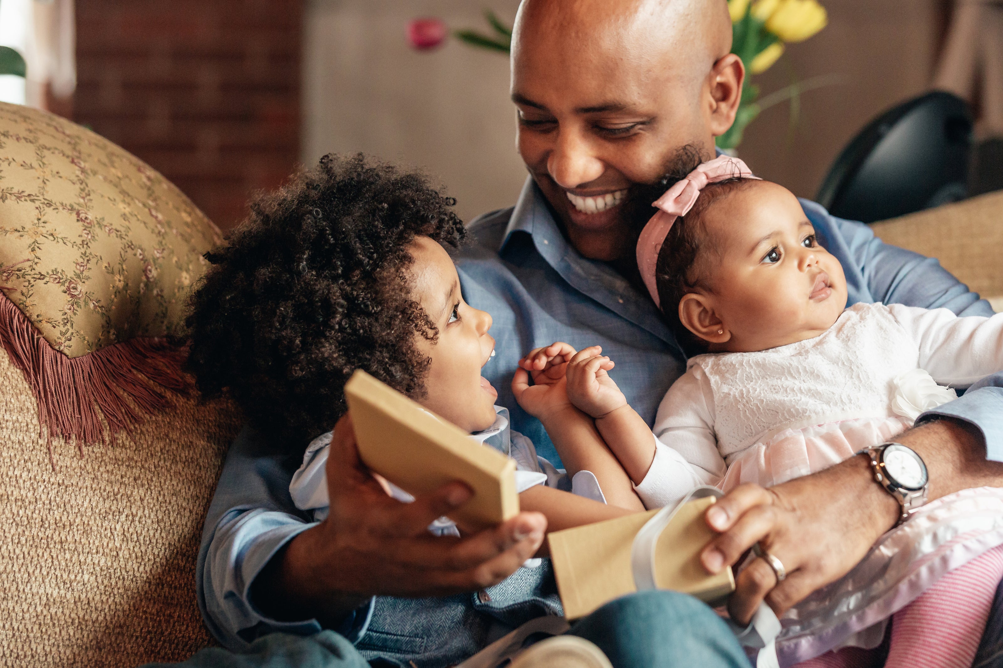 young-boy-smiles-at-father-holding-baby-sister